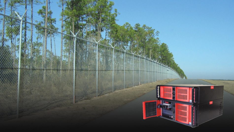 FiberPatrol FP1100 fiber optic fence-mounted intrusion detection sensor processor inset in image of product on a fenceline along a road