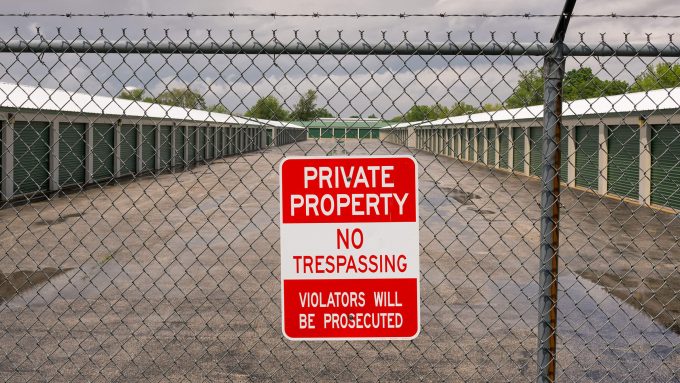Outdoor storage unit facility protected by a barbed wire fence and private property sign, representing Senstar's relevance to the commercial industry