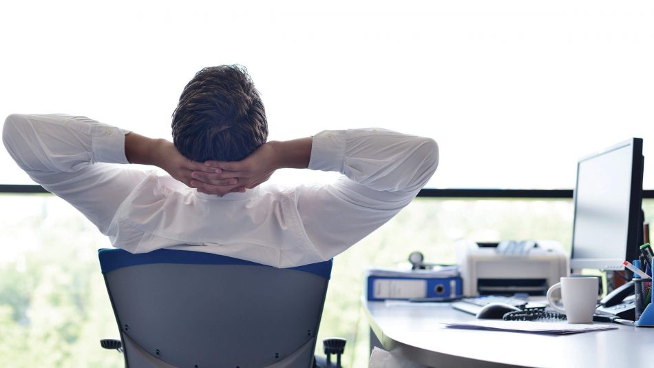 La espalda del hombre en la silla con las manos cruzadas detrás de la cabeza para representar la reducción del estrés proporcionado por el programa Senstar Care