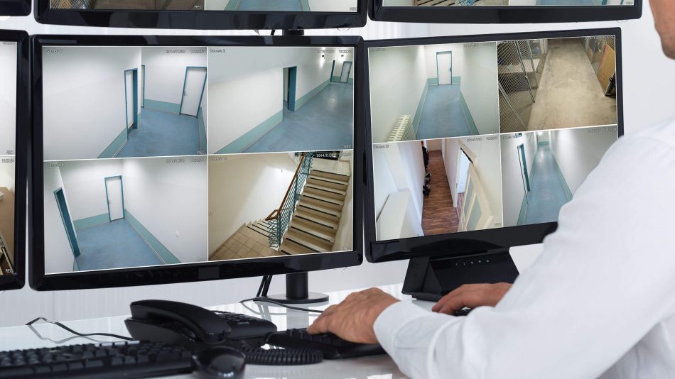 Man sitting at monitors showing Symphony Access Control's integration with Senstar Symphony video, security and information management platform