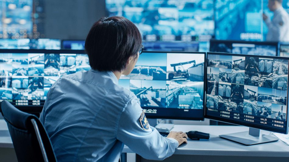 Security guard at multiple monitors to show how Thin Client provides live video feeds of specific cameras to third-party security contractors without granting direct server access