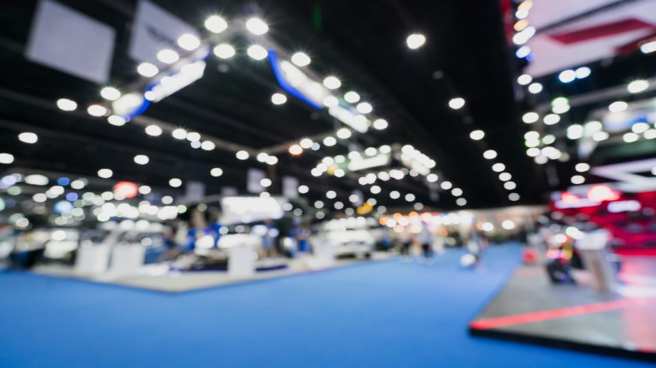 Blurred image of a tradeshow floor with booths along a pathway